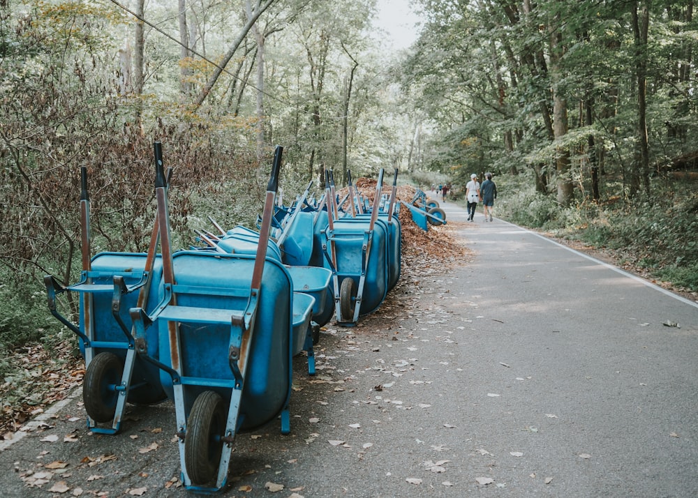 a row of blue carts sitting on the side of a road