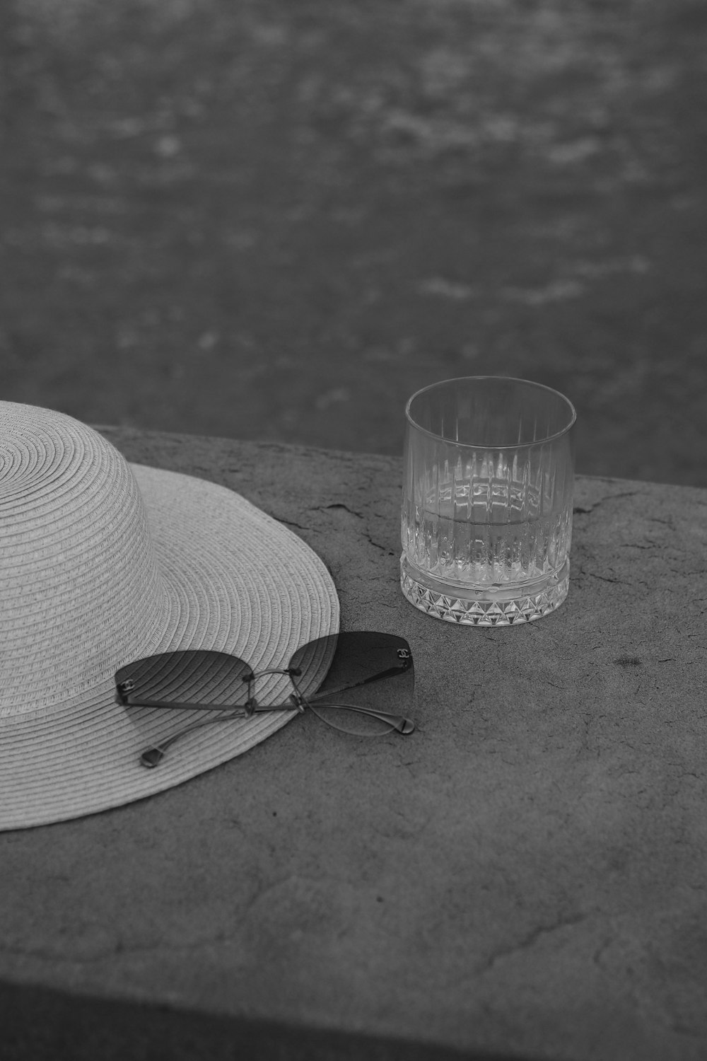 a hat, sunglasses and a glass sitting on a ledge