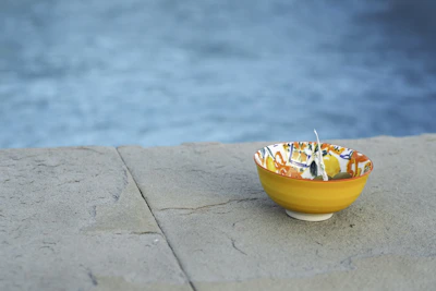 Close-up of a colorful ceramic bowl with swirling patterns of orange, blue, and green, showcasing the texture of the clay.