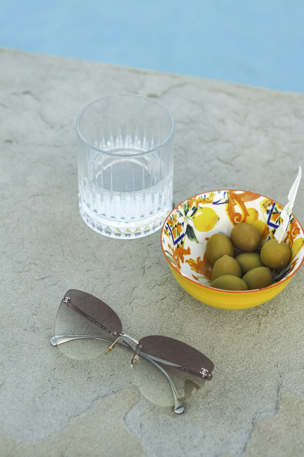 a bowl of olives next to a pair of glasses