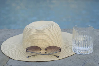 A bright, cheerful sun hat resting on a wooden table with a soft summer background.