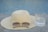 A stylish sun hat displayed on a wooden table with a beach background.