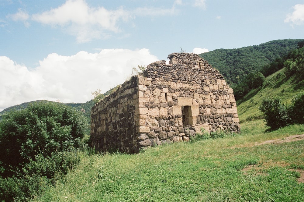a stone building sitting on top of a lush green hillside