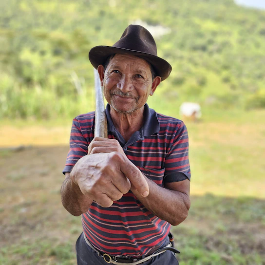 Elderly man in hat holding a tool outdoors