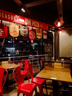 Happy customers enjoying pizza slices at a cozy table bathed in warm red lighting