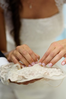 Close-up of hands carefully repairing a delicate lace fabric on an antique dress.