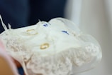 A close-up of wedding rings on a decorative cushion.