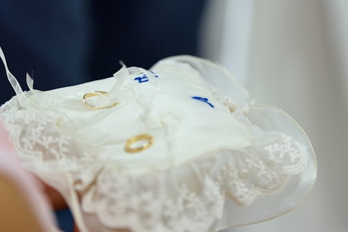 A close-up of wedding rings on a decorative cushion.