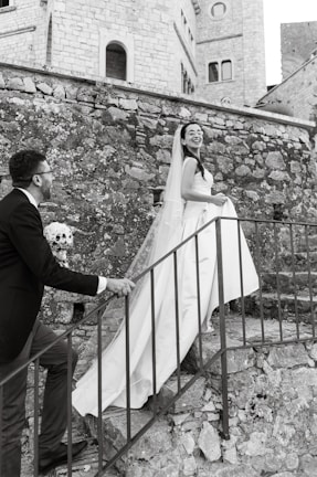 Bride and groom laughing together on a sandstone staircase, framed by intricate Jaipuri patterns.
