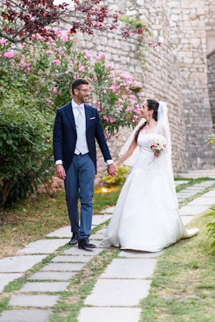 The bride and groom walking hand-in-hand down a garden path at sunset.