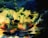 A textured and abstract composition featuring swirling patterns of green, blue, yellow, and red. The colors blend together, creating shapes that resemble nature-inspired forms or surreal landscapes. The paint appears layered and dynamic, with a glossy finish reflecting light.