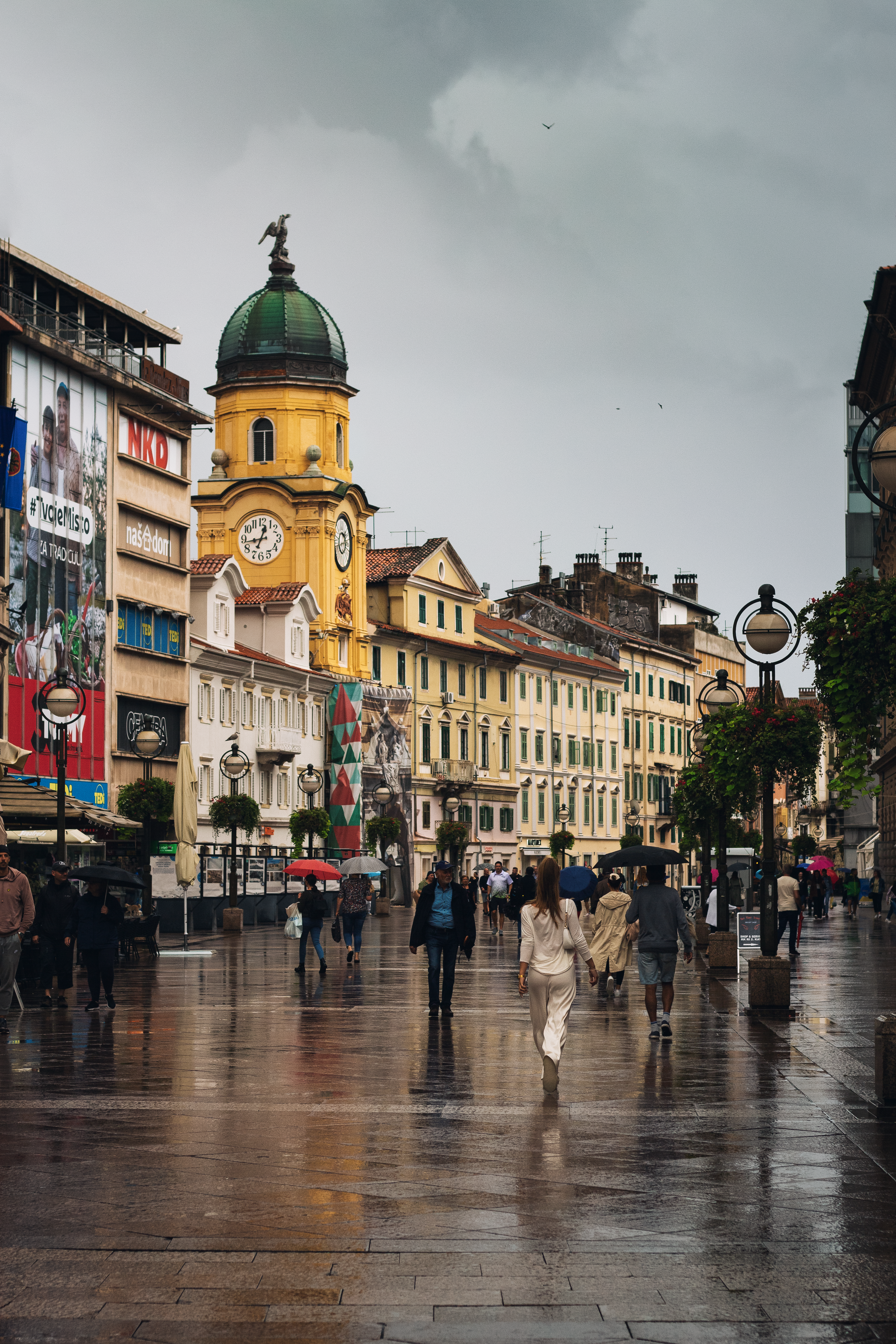 a group of people walking down a street next to tall buildings