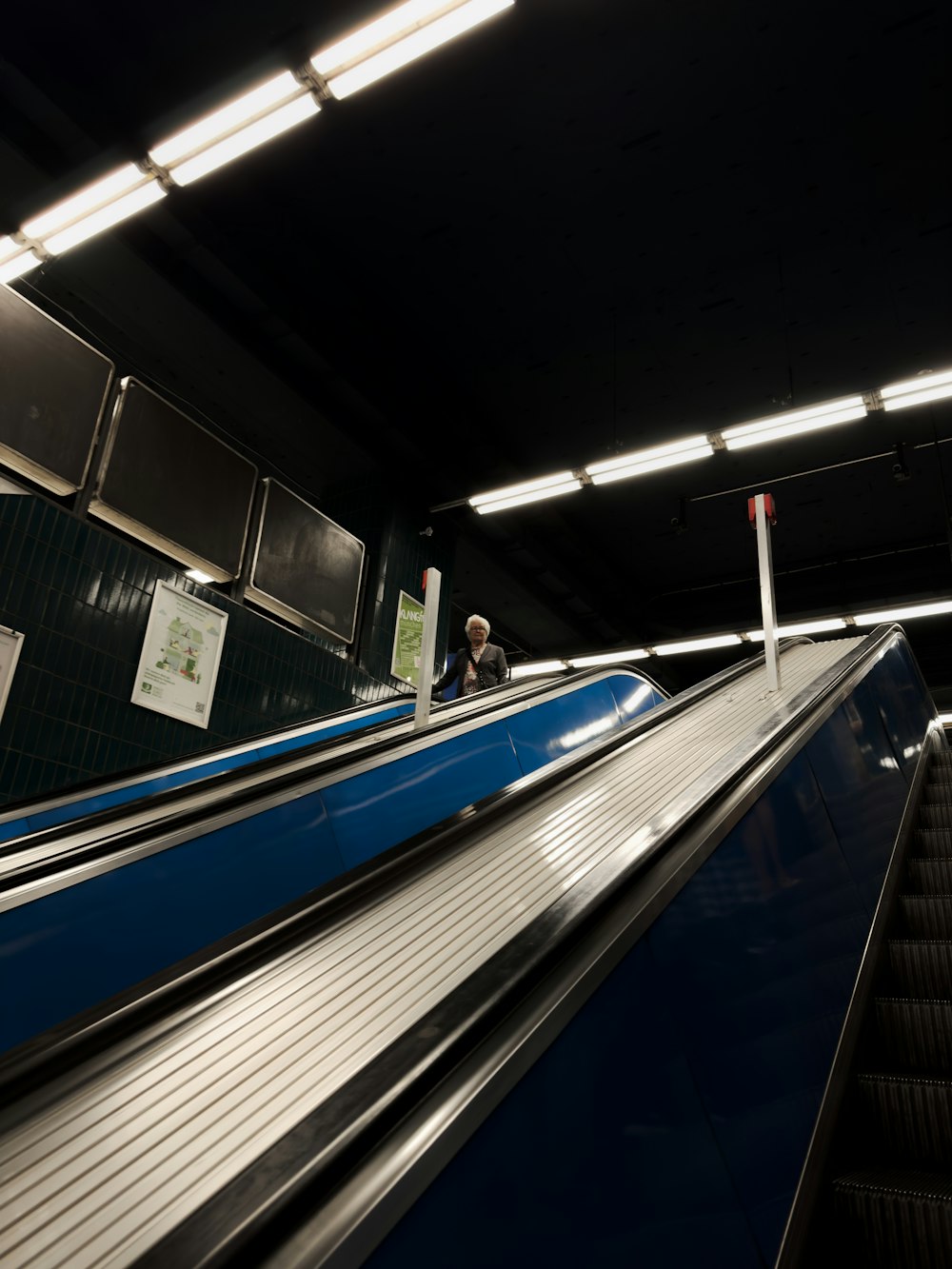 uma pessoa andando em uma escada rolante em uma estação de metrô