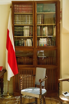 Books and legal codes stacked on a wooden desk with a Colombian flag.