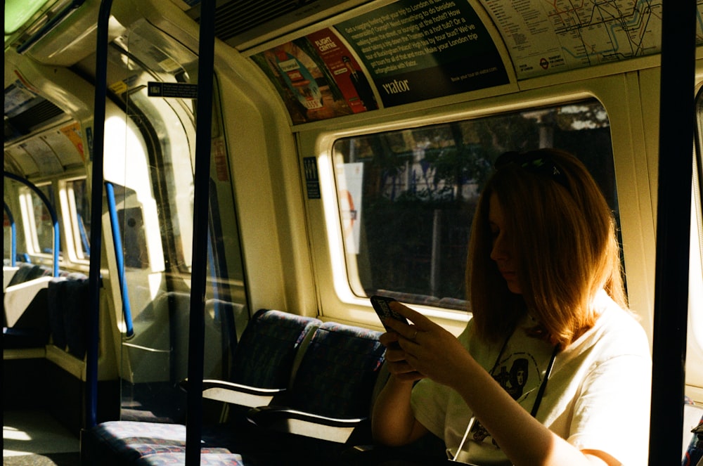a woman sitting on a train looking at her phone