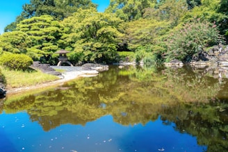 A tranquil garden near a sacred pond, reflecting the blue sky and surrounding greenery.