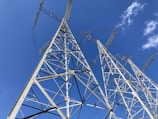 A wide shot of a modern power station with tall transmission towers against a clear blue sky.