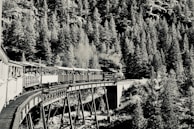 Black-and-white image of a rare early 1900s steam locomotive crossing a rural bridge.
