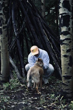 Volunteers gently rescuing a frightened dog from a forested area.