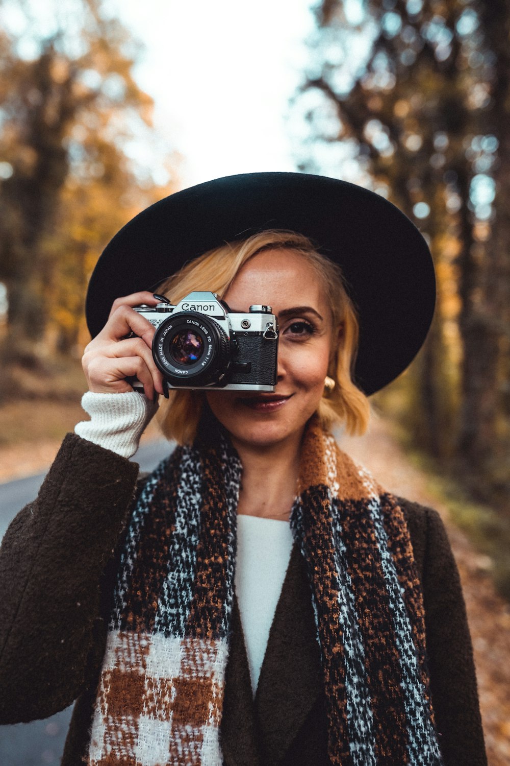 a woman wearing a hat and scarf holding a camera