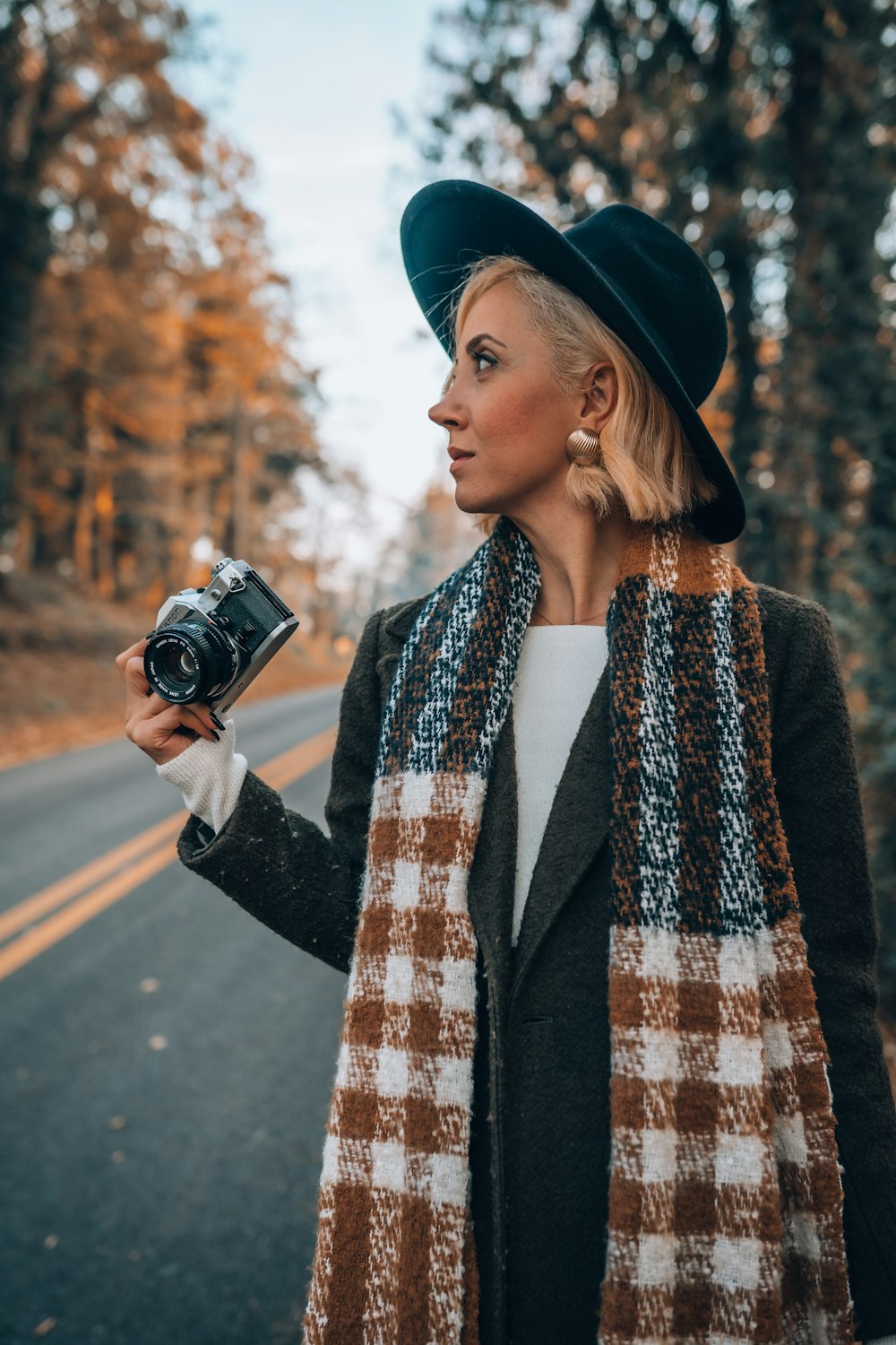a woman in a hat and scarf holding a camera