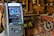 An ATM situated indoors among various wooden and metal antique machinery, creating a juxtaposition between modern technology and historical equipment.