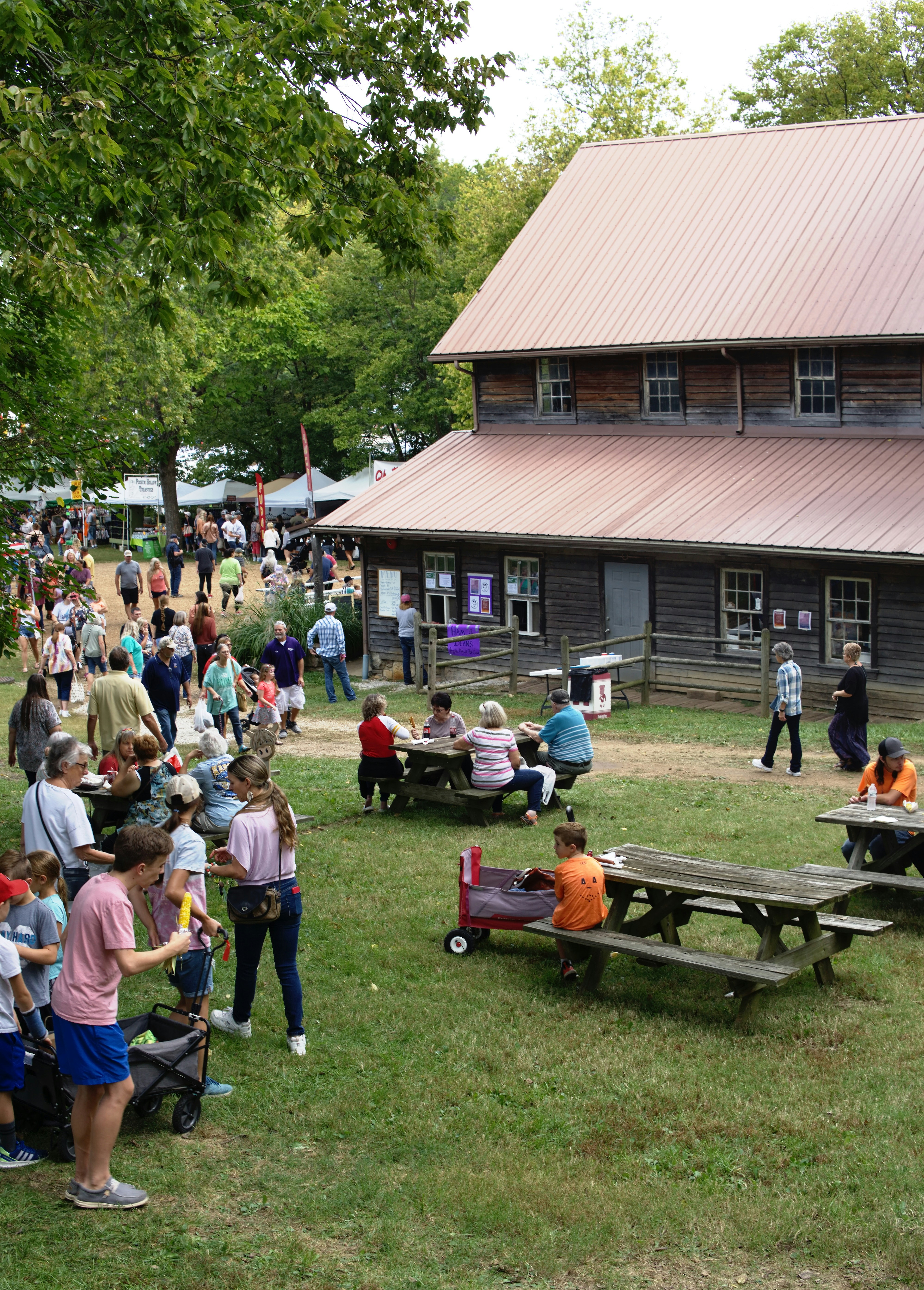 A lively outdoor farm event with families enjoying activities and animals.