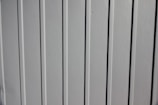 A close-up view of a vertical panel construction with subtle grooves and an off-white or light gray color.