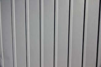 A close-up view of a vertical panel construction with subtle grooves and an off-white or light gray color.