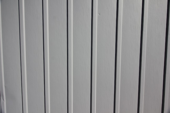 A close-up view of a vertical panel construction with subtle grooves and an off-white or light gray color.