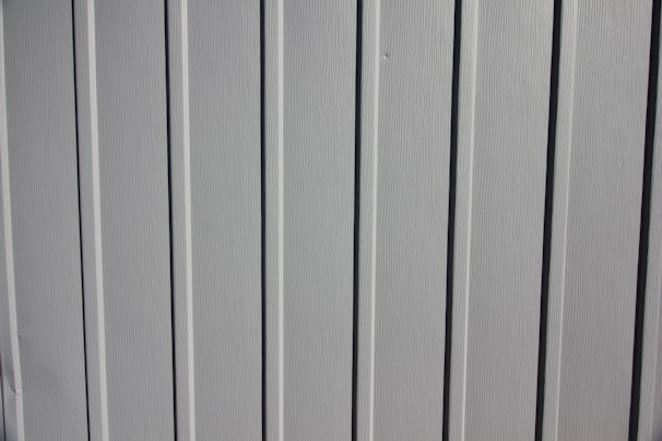 A close-up view of a vertical panel construction with subtle grooves and an off-white or light gray color.