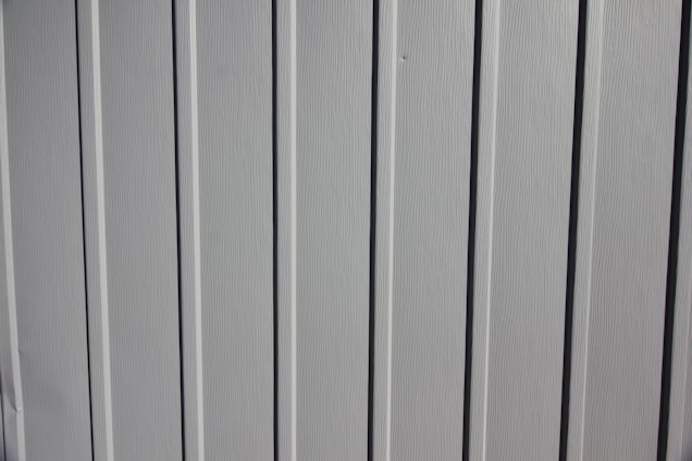 A close-up view of a vertical panel construction with subtle grooves and an off-white or light gray color.