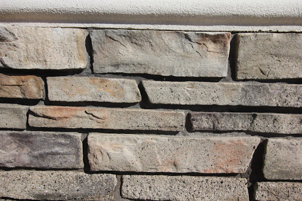 High-resolution shot of a modern stone wall featuring large rectangular tiles in varying shades of grey.
