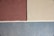 Three sections of textured wall in shades of brown, beige, and blue are separated by white lines. The top left section is brown, the top right is beige, and the bottom section is a cool blue. The texture appears to be plastered, giving a rough and natural finish.