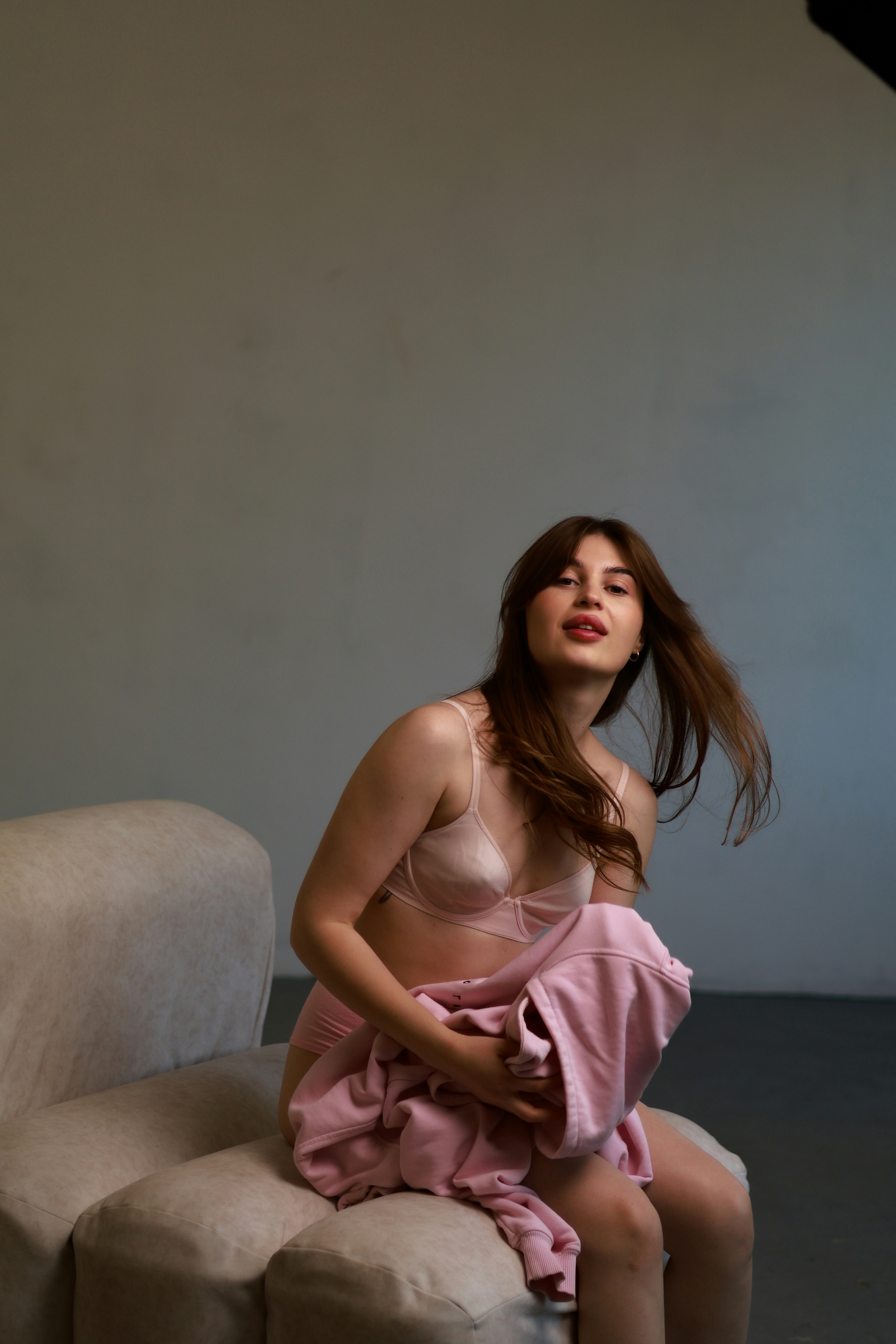 a woman in a pink dress sitting on a couch