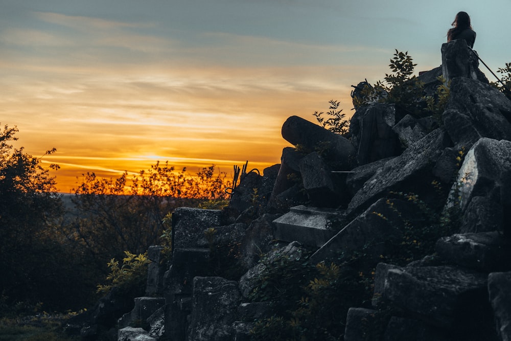 a woman standing on top of a pile of rocks