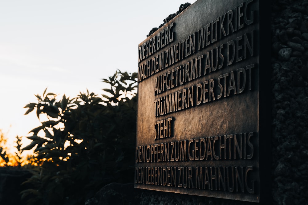 a close up of a metal sign near a bush