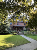 Charming green house with a welcoming front porch and flowering plants.
