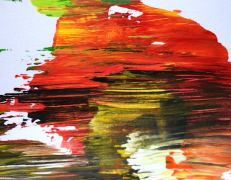 A close-up of bold brushstrokes blending warm and cool tones on a textured canvas.