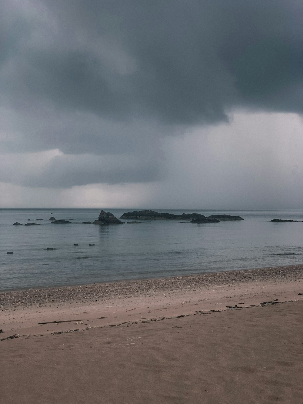 a person walking on a beach under a cloudy sky
