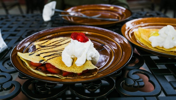 A plate of pancakes with whipped cream and strawberries