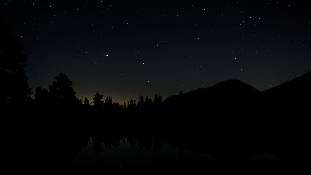 the night sky is reflected in the still water of a lake