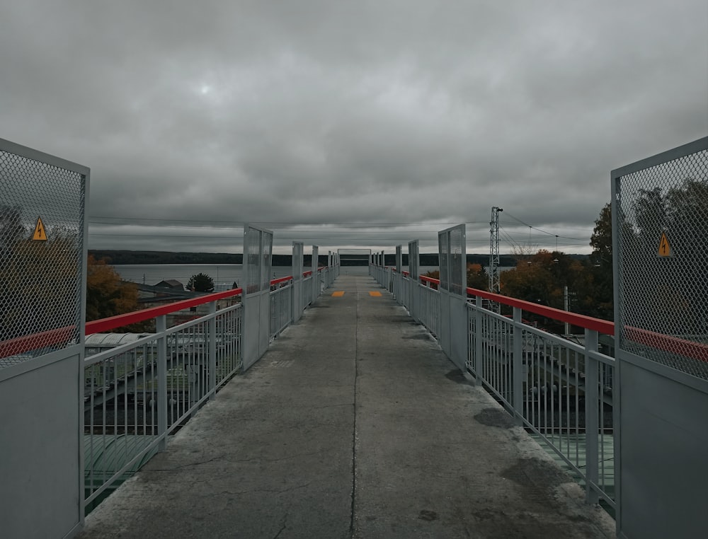 a bridge with a red railing and a cloudy sky