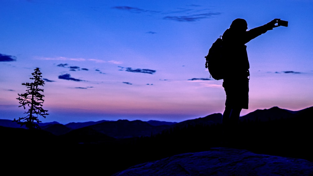 a silhouette of a person taking a picture with a camera