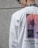 A person is wearing a white shirt featuring abstract designs with red and black elements and the text 'Old Stories... New Times.' The shirt also includes repetitive text 'THE LAST FEELINGS' along the design. The person is wearing sunglasses and has a floral pattern on the collar of a shirt visible underneath.