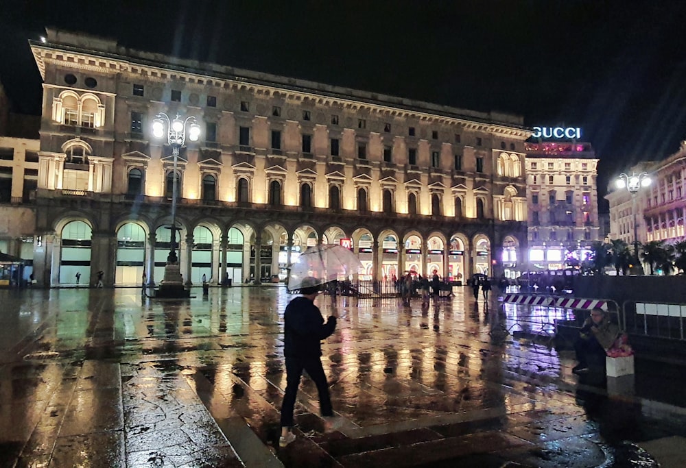 a man standing on a wet sidewalk in front of a building