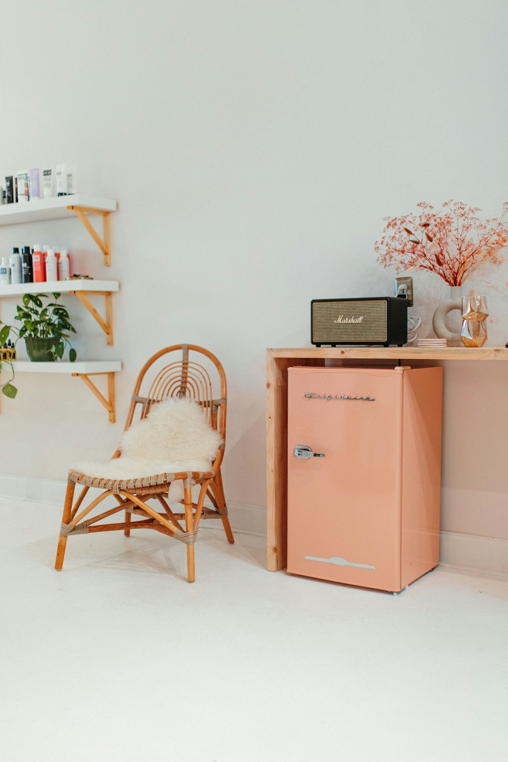 a pink refrigerator sitting next to a wooden chair