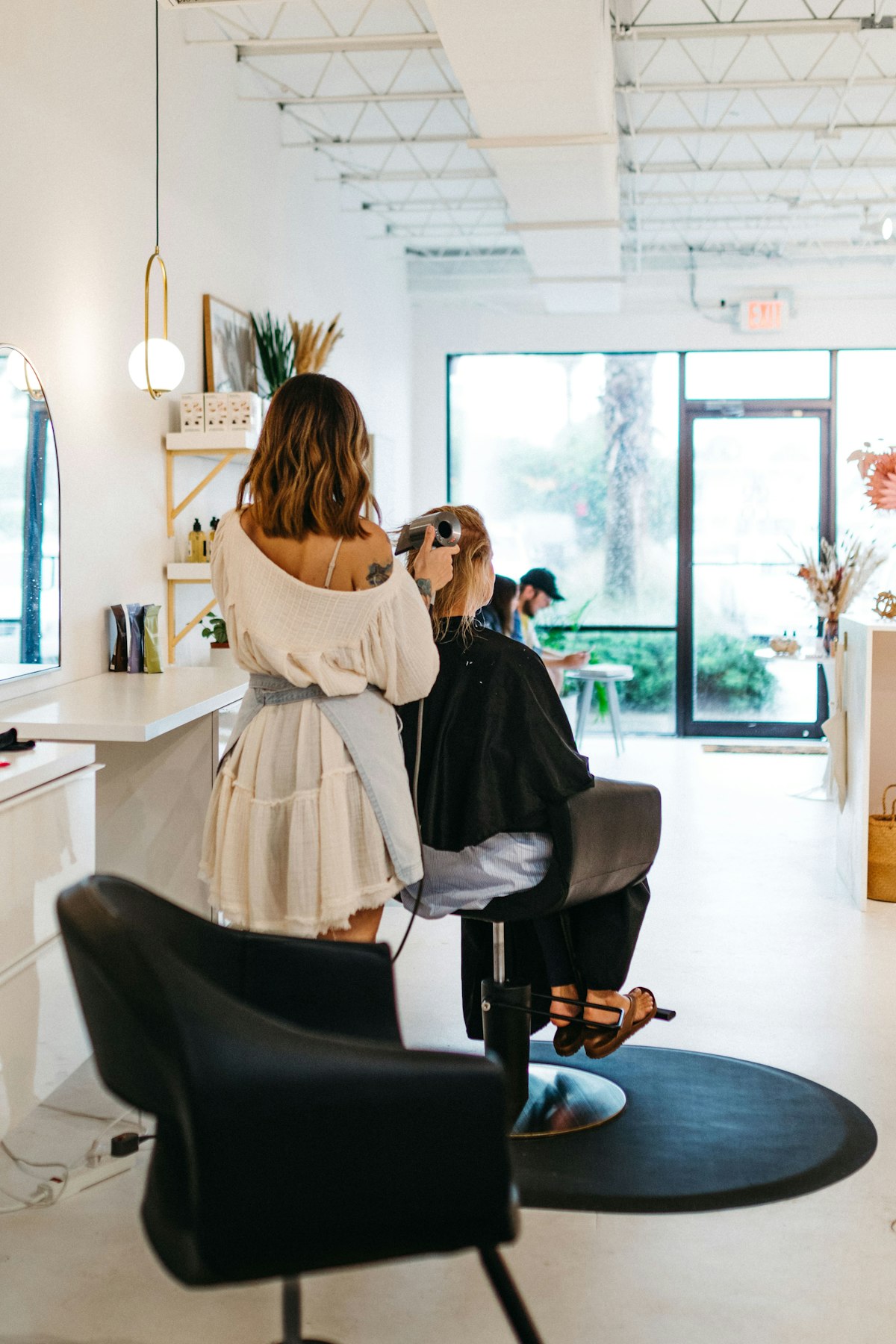 Hair stylist blow-drying a client's hair in a bright modern salon