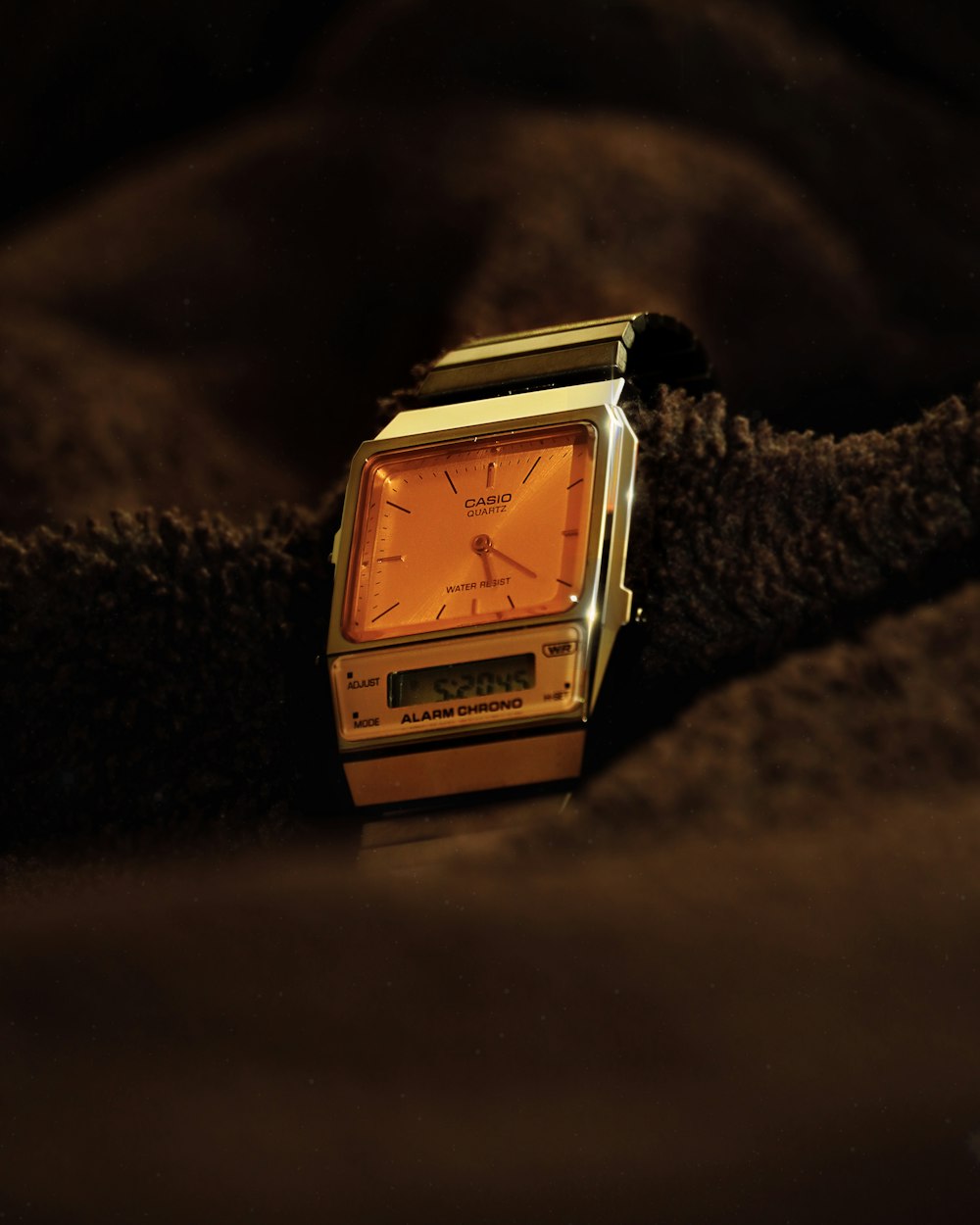 a watch sitting on top of a brown blanket