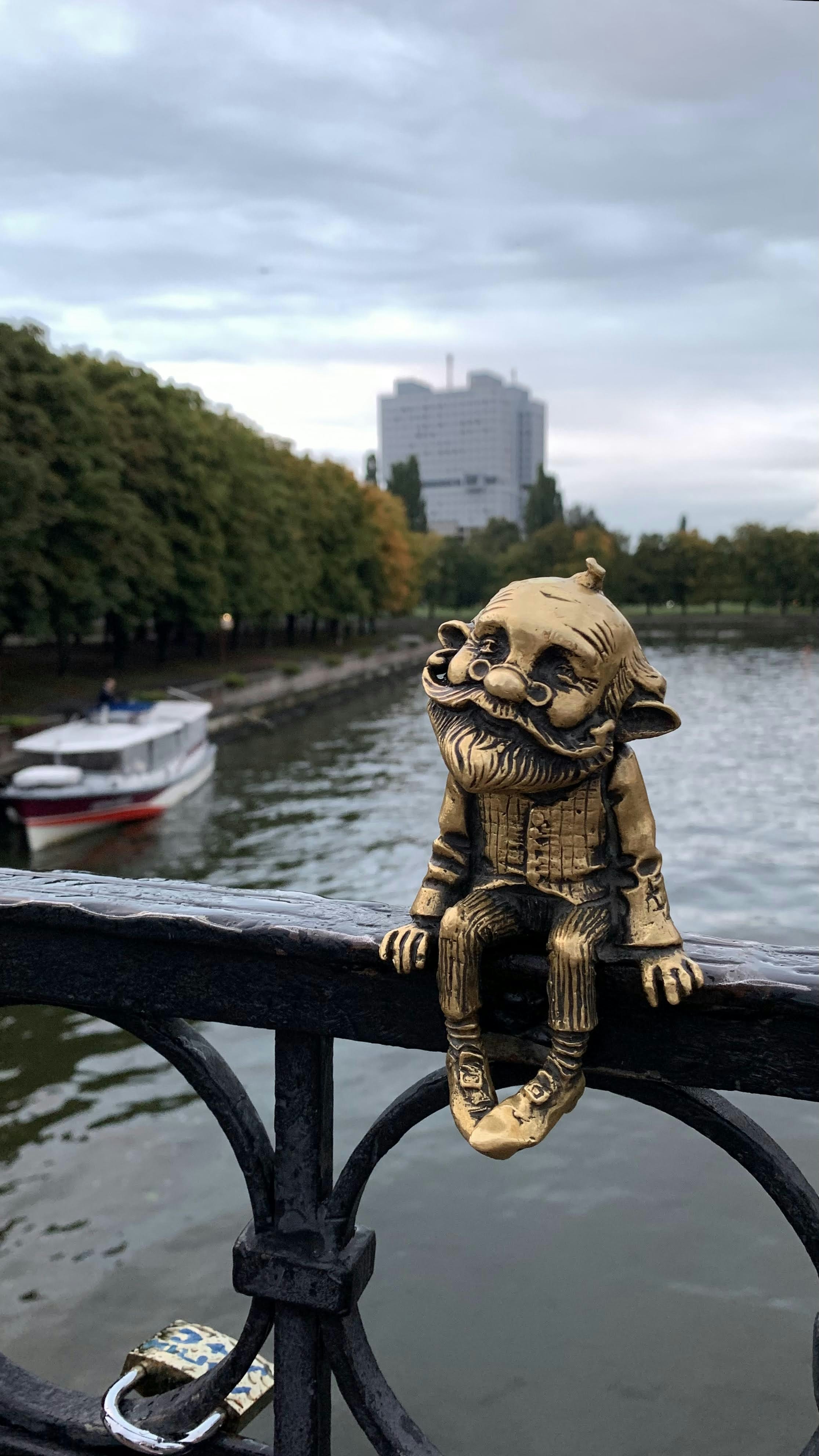 a statue of a cat sitting on a fence next to a body of water